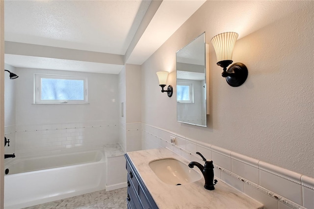 bathroom featuring a washtub, vanity, and a healthy amount of sunlight