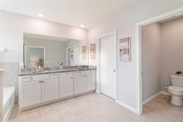 bathroom featuring vanity, toilet, and tiled tub