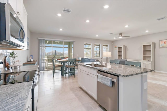 kitchen featuring ceiling fan, white cabinetry, sink, an island with sink, and appliances with stainless steel finishes