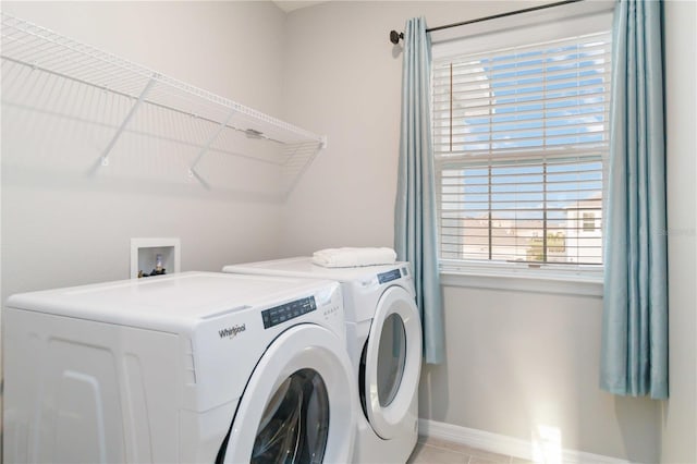 clothes washing area with separate washer and dryer, a wealth of natural light, and light tile patterned floors