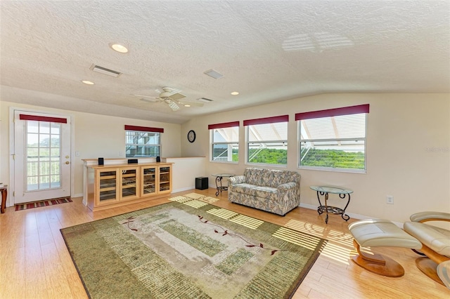 living room with ceiling fan, plenty of natural light, hardwood / wood-style floors, and vaulted ceiling