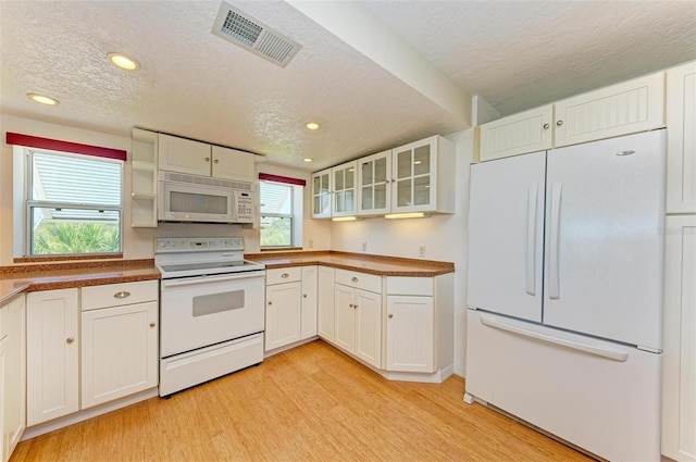 kitchen with light hardwood / wood-style floors, white cabinetry, white appliances, and a textured ceiling