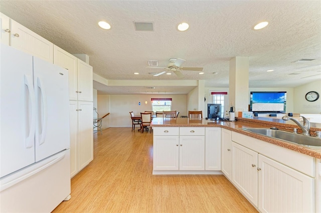 kitchen featuring a textured ceiling, white refrigerator, white cabinetry, and sink