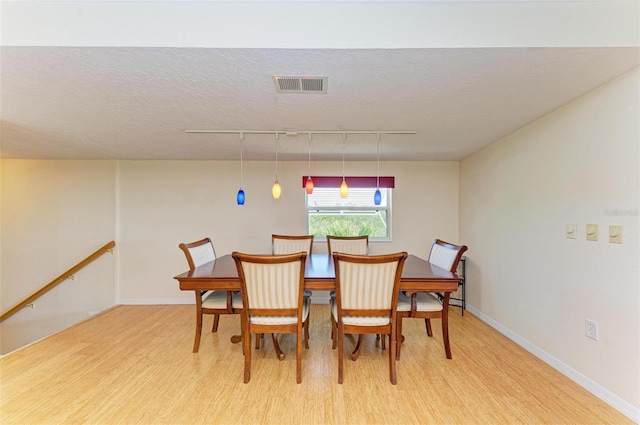 dining room with a textured ceiling, track lighting, and light wood-type flooring