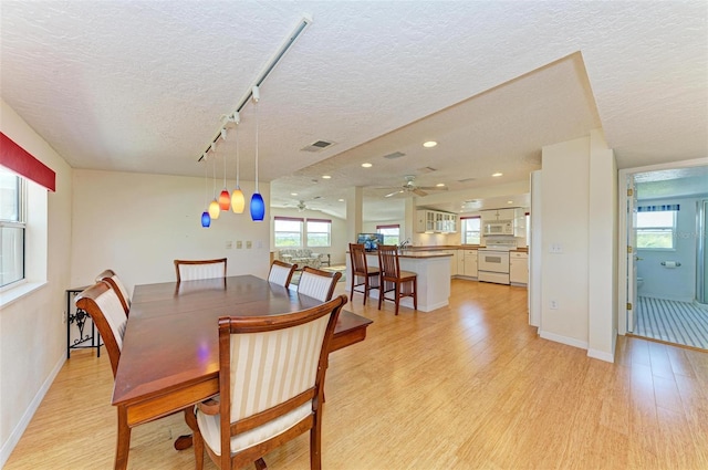 dining room with a textured ceiling, light hardwood / wood-style floors, track lighting, and ceiling fan