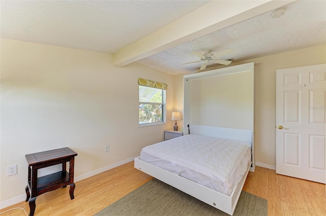 bedroom featuring hardwood / wood-style flooring, ceiling fan, beam ceiling, and a textured ceiling