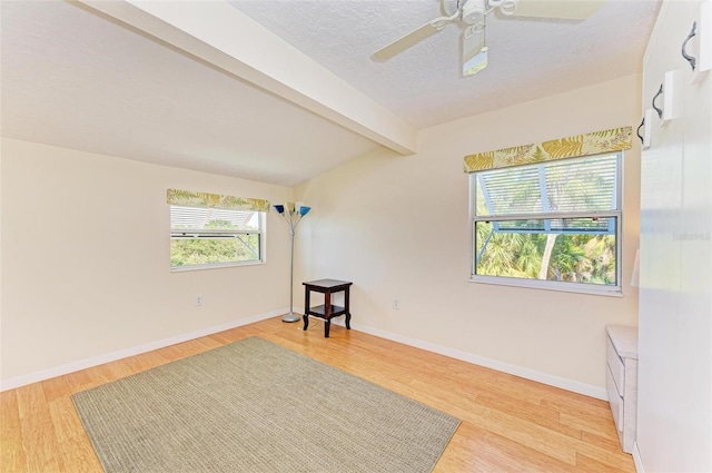 unfurnished room with beamed ceiling, light hardwood / wood-style floors, and plenty of natural light