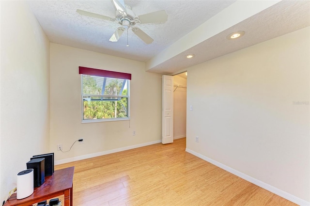 empty room featuring ceiling fan, light hardwood / wood-style floors, and a textured ceiling