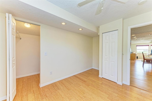 unfurnished bedroom with a textured ceiling, light wood-type flooring, a closet, and ceiling fan