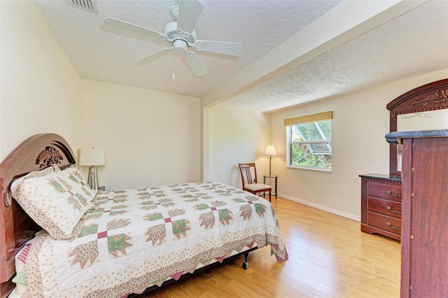 bedroom featuring ceiling fan, a textured ceiling, and light hardwood / wood-style flooring