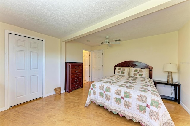 bedroom featuring ceiling fan, beamed ceiling, a textured ceiling, a closet, and light wood-type flooring