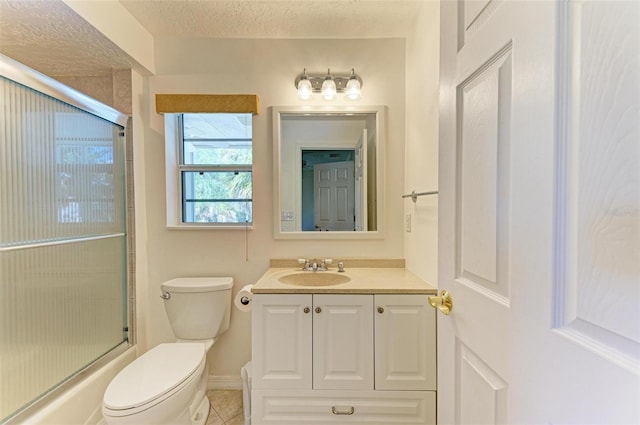 full bathroom featuring a textured ceiling, vanity, shower / bath combination with glass door, tile patterned flooring, and toilet