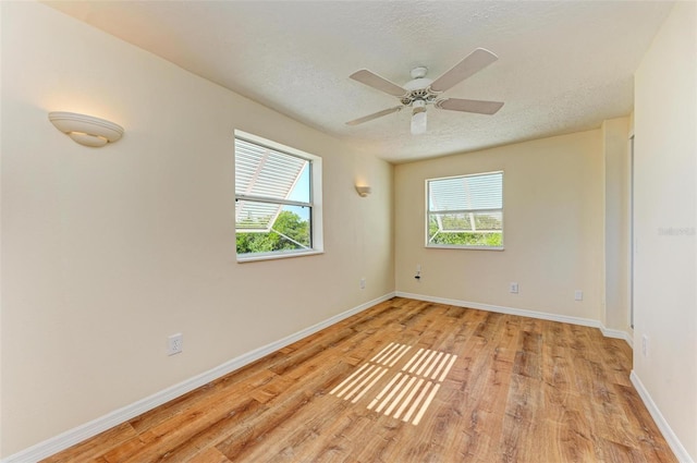 unfurnished room with ceiling fan, a healthy amount of sunlight, a textured ceiling, and light hardwood / wood-style floors