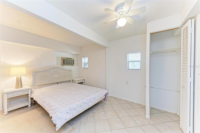 tiled bedroom with a wall mounted air conditioner, a textured ceiling, a closet, and ceiling fan