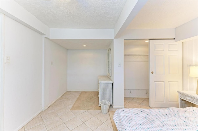 tiled bedroom with a textured ceiling and a closet