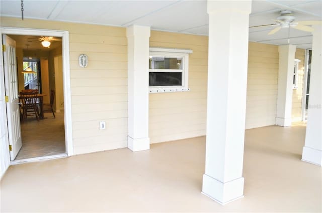 interior space featuring wooden walls, ceiling fan, and concrete flooring