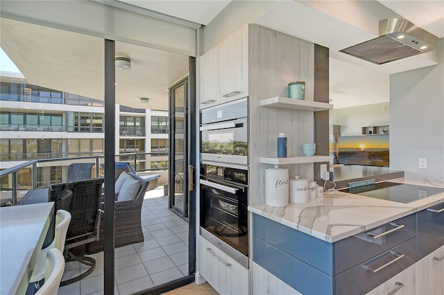 kitchen with cooktop, light stone counters, light tile patterned flooring, and a healthy amount of sunlight