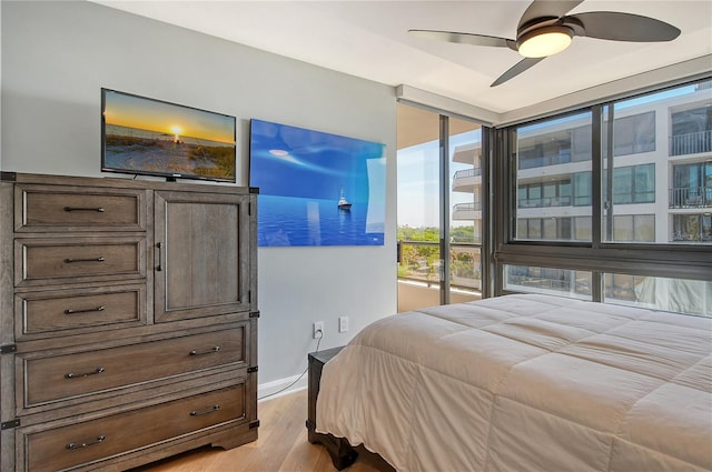 bedroom with ceiling fan, expansive windows, and light hardwood / wood-style floors