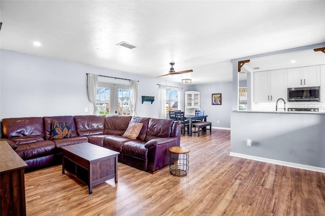 living room featuring french doors, sink, ceiling fan, and light hardwood / wood-style floors