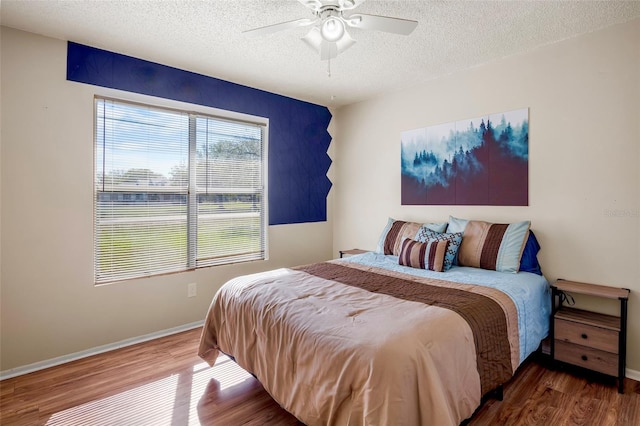 bedroom with a textured ceiling, wood-type flooring, and ceiling fan