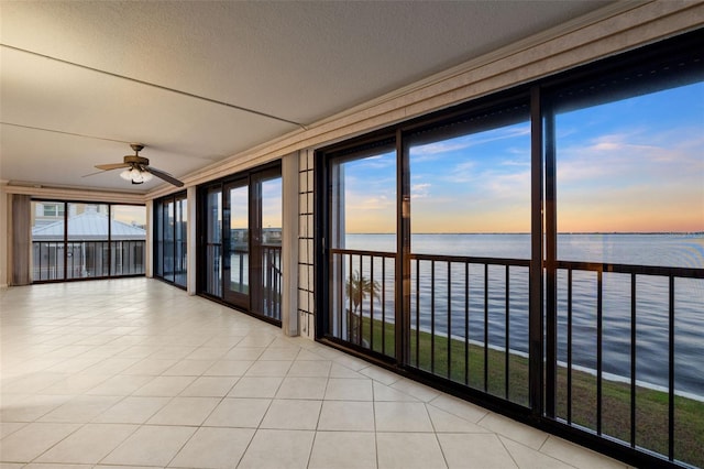 unfurnished sunroom featuring ceiling fan and a water view