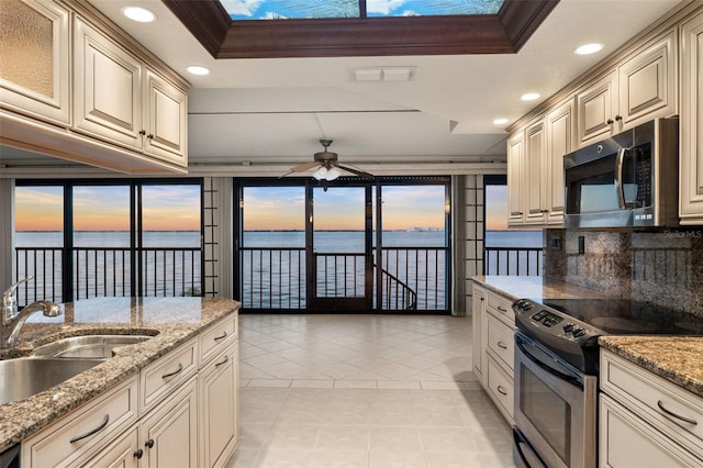 kitchen featuring a water view, stainless steel appliances, ornamental molding, and a raised ceiling