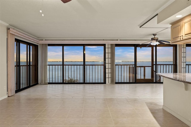 unfurnished room with ceiling fan, light tile patterned flooring, a water view, and a wealth of natural light