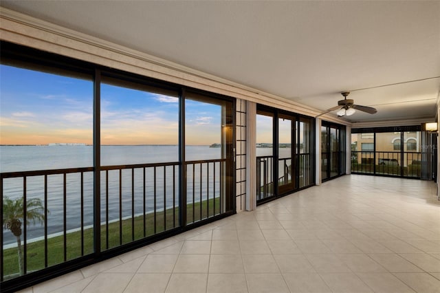 unfurnished sunroom featuring ceiling fan and a water view