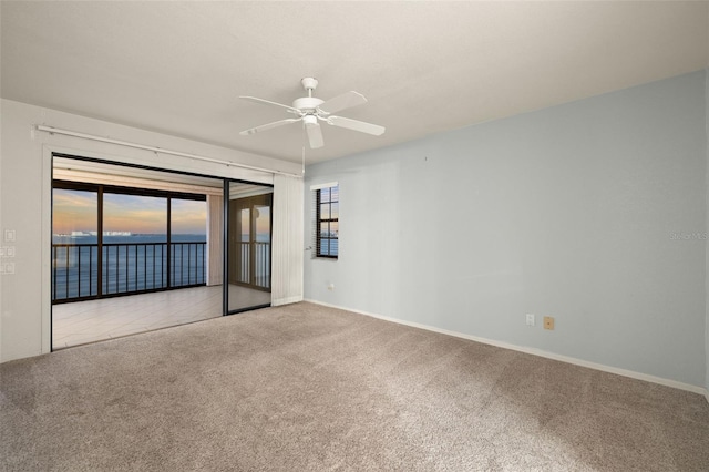 carpeted spare room featuring ceiling fan, plenty of natural light, and a water view