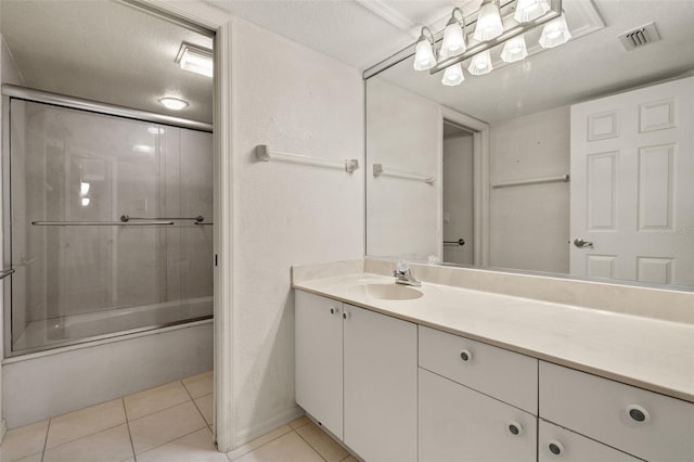 bathroom with bath / shower combo with glass door, tile patterned flooring, vanity, and a textured ceiling