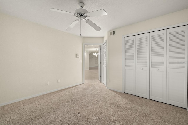 unfurnished bedroom with light carpet, a closet, and ceiling fan with notable chandelier