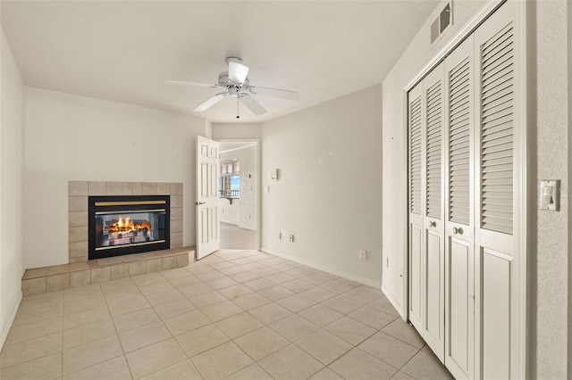 unfurnished living room with ceiling fan, light tile patterned flooring, and a tile fireplace