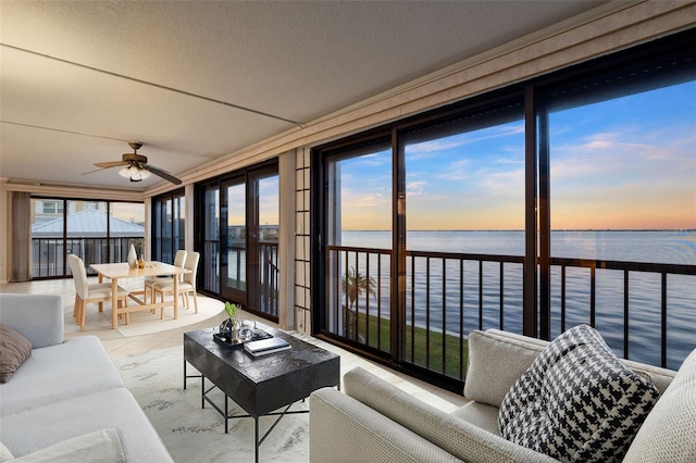 sunroom featuring ceiling fan and a water view