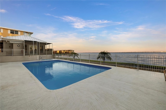 pool at dusk featuring a patio area and a water view