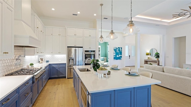 kitchen featuring sink, blue cabinetry, white cabinets, a center island with sink, and custom exhaust hood