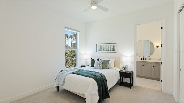 bedroom with multiple windows, ensuite bathroom, light colored carpet, and ceiling fan