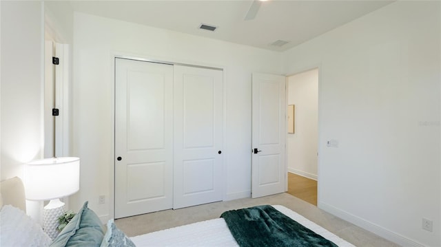 bedroom with ceiling fan, light colored carpet, and a closet