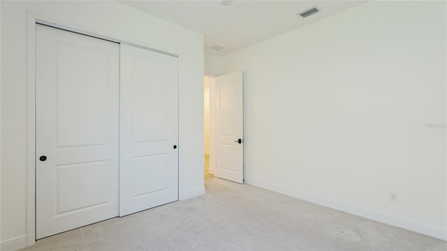 unfurnished bedroom with light colored carpet and a closet