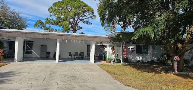 view of front of home featuring a front yard, a carport, driveway, and stucco siding