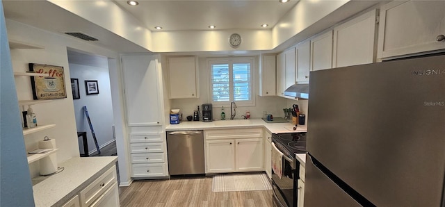 kitchen with light wood finished floors, a sink, light countertops, under cabinet range hood, and appliances with stainless steel finishes