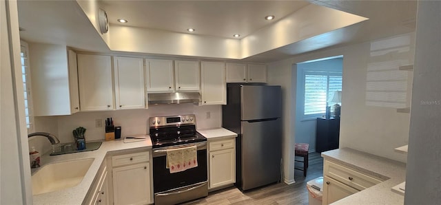 kitchen with appliances with stainless steel finishes, light hardwood / wood-style flooring, white cabinetry, and sink