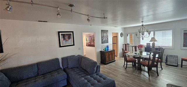 living room with hardwood / wood-style flooring, rail lighting, and an inviting chandelier