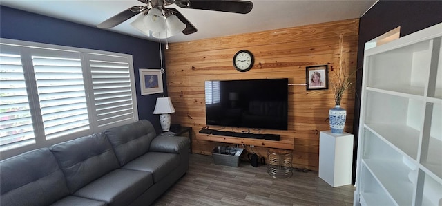 living room featuring hardwood / wood-style flooring, ceiling fan, and wood walls