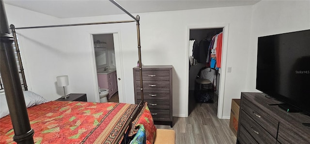 bedroom featuring a spacious closet, light hardwood / wood-style flooring, and ensuite bath