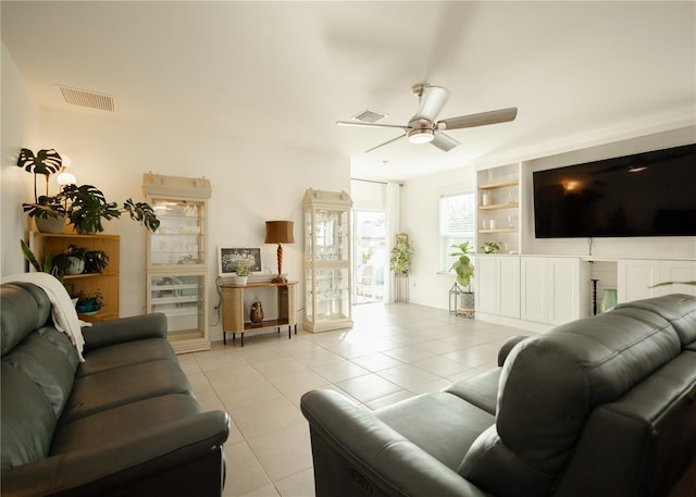 living room with built in shelves, ceiling fan, and light tile patterned flooring