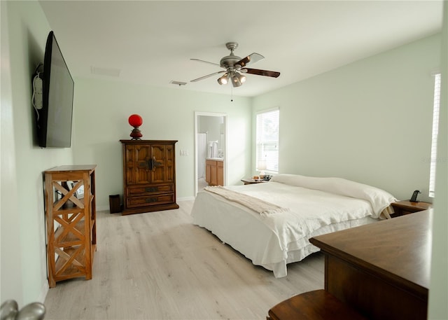 bedroom with ceiling fan, light wood-type flooring, and ensuite bath