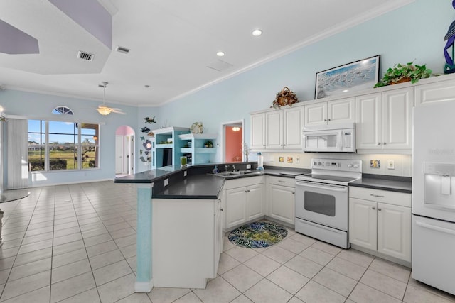 kitchen with white appliances, arched walkways, dark countertops, open floor plan, and a peninsula