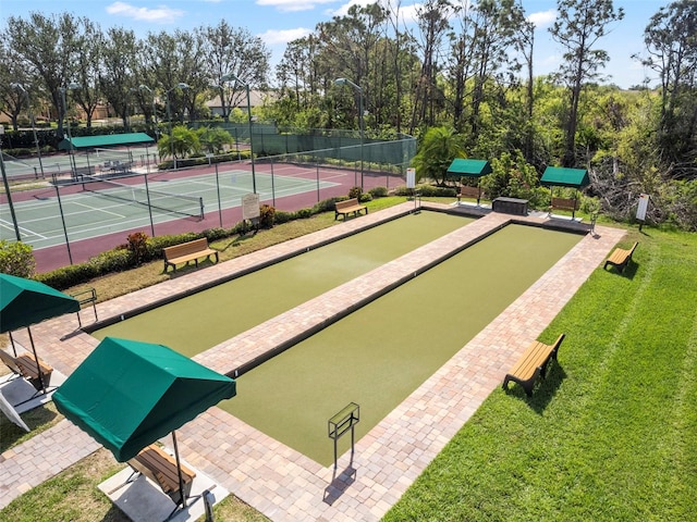 surrounding community featuring a tennis court, fence, and a lawn