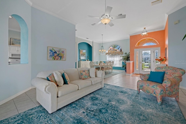 tiled living area featuring arched walkways, crown molding, baseboards, and ceiling fan with notable chandelier