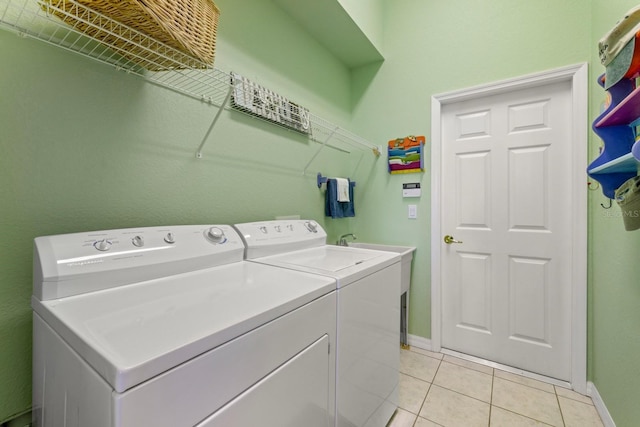 washroom with laundry area, light tile patterned floors, baseboards, and washing machine and clothes dryer